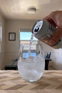 Tonic water being poured into a glass cup.