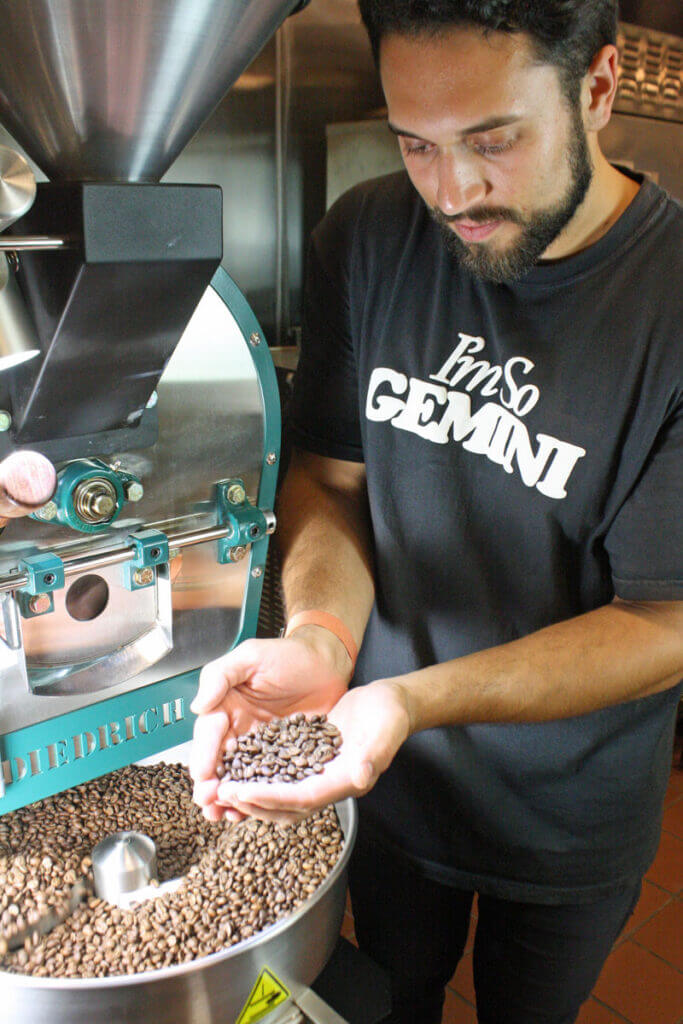 Noah from Anomaly Coffee Company holding coffee beans